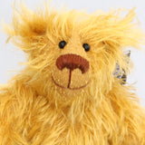 Billy McCubbin is made from a a fluffy medium length gold mohair, that is it would be a medium length mohair on a big bear but on such a little bear it's very long and fluffy. Billy's paw pads are made from the same mohair, trimmed down to the finest stubble.  Billy McCubbin has small spherical glass eyes, that catch the light whichever way you look at him, he has a pert little nose embroidered from fine brown perle cotton and a beaming smile