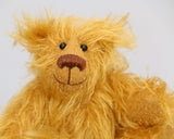 Billy McCubbin is made from a a fluffy medium length gold mohair, that is it would be a medium length mohair on a big bear but on such a little bear it's very long and fluffy. Billy's paw pads are made from the same mohair, trimmed down to the finest stubble.  Billy McCubbin has small spherical glass eyes, that catch the light whichever way you look at him, he has a pert little nose embroidered from fine brown perle cotton and a beaming smile
