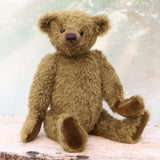 brownish-green teddy bear on a wooden surface with a soft, blurred background