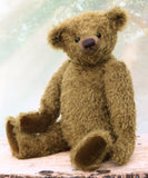 brownish-green teddy bear on a wooden surface with a blurred light background