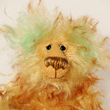 Green Eared Banana Stalker is a little, endearingly sweet and joyful, one of a kind, artist bear by Barbara-Ann Bears in wonderfully fluffy mohair, he stands 6.5 inches/17 cm tall. He is mostly made from a long golden mohair with brown tipping, with hand dyed green mohair ears, and beige wool felt paw pads. He has hand painted glass eyes with hand coloured eyelids, a wonderfully embroidered nose and a broad and cheerful smile.