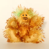 Green Eared Banana Stalker is a little, endearingly sweet and joyful, one of a kind, artist bear by Barbara-Ann Bears in wonderfully fluffy mohair, he stands 6.5 inches/17 cm tall. He is mostly made from a long golden mohair with brown tipping, with hand dyed green mohair ears, and beige wool felt paw pads. He has hand painted glass eyes with hand coloured eyelids, a wonderfully embroidered nose and a broad and cheerful smile.