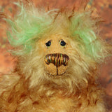 Green Eared Banana Stalker is a little, endearingly sweet and joyful, one of a kind, artist bear by Barbara-Ann Bears in wonderfully fluffy mohair, he stands 6.5 inches/17 cm tall. He is mostly made from a long golden mohair with brown tipping, with hand dyed green mohair ears, and beige wool felt paw pads. He has hand painted glass eyes with hand coloured eyelids, a wonderfully embroidered nose and a broad and cheerful smile.