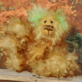 Green Eared Banana Stalker is a little, endearingly sweet and joyful, one of a kind, artist bear by Barbara-Ann Bears in wonderfully fluffy mohair, he stands 6.5 inches/17 cm tall. He is mostly made from a long golden mohair with brown tipping, with hand dyed green mohair ears, and beige wool felt paw pads. He has hand painted glass eyes with hand coloured eyelids, a wonderfully embroidered nose and a broad and cheerful smile.