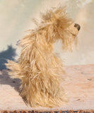 Beige fluffy teddy bear on a wooden surface with a blurred background