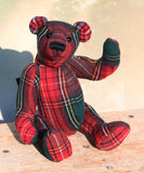 Red plaid teddy bear on a wooden surface with a blurred background