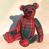 Plaid teddy bear on a wooden surface with a light background