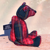 Plaid fabric bear on a wooden surface with a blurred background