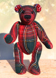 Plaid teddy bear standing on a wooden surface with a blurred background