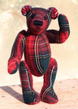 Waving plaid teddy bear standing on a wooden surface with a blurred background