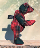 Plaid teddy a bear on a wooden surface with a blurred background