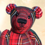Plaid teddy bear with a red and black pattern on a beige background