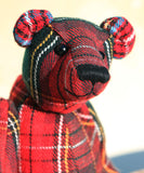 Plaid teddy bear with a black button nose on a blurred background