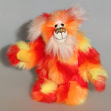 Sunny is a flamboyant, fun-loving and comical, one of a kind, artist bear by Barbara-Ann Bears in luxurious mohair and beautifully colourful faux fur and he stands 11.5 inches/29 cm tall and is 9 inches/23cm sitting.  Sunny is made from a beautiful faux fur in bright yellow, orange and red, his face the fronts of his ears and the underside of his tail are a long white fluffy mohair and he has bright gold wool felt paw pads