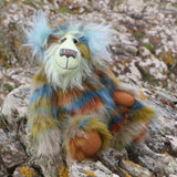 Colourful teddy bear sitting on a rocky outcrop