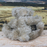 Wolfie sitting, viewed from behind.
Wolfie is a wild and groovy guy, a veteran artist bear from Barbara-Ann Bears in silvery grey English mohair, he stands 10 inches/25 cm tall.