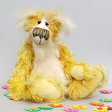 Alfredo Buttercup, a comical yet elegant yellow and white, one of a kind artist teddy bear in stunning hand dyed mohair by Barbara-Ann Bears. Alfredo Buttercup stands 17 inches (43 cm) tall and is 13 inches (33 cm) sitting. He is mostly made from a long and straggly mohair hand-dyed in sunny shades of yellow and gold.