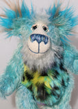 Billy Calypso has beautiful hand painted eyes with eyelids, a nose embroidered from individual threads to complement his colouring and he has a huge, friendly smile. Billy's face is a long and fluffy white mohair with blue tipping. On top of Billy's head and on the backs of his ears is a very long aqua faux fur with tufts of warm beige.