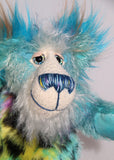 Billy Calypso has beautiful hand painted eyes with eyelids, a nose embroidered from individual threads to complement his colouring and he has a huge, friendly smile. Billy's face is a long and fluffy white mohair with blue tipping. On top of Billy's head and on the backs of his ears is a very long aqua faux fur with tufts of warm beige.