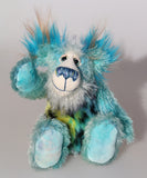 Billy Calypso is made from a sparse mohair hand dyed sky blue, his tummy is a long blue, yellow and magenta faux fur with black spots and his face and the underside of his tail are a long white mohair with blue tipping. On top of Billy's head and on the backs of his ears is a long aqua faux fur with tufts of warm beige. Billy has hand-dyed velvet paw pads. Billy has beautiful hand painted eyes with eyelids, a nose embroidered from individual threads and he has a huge, friendly smile