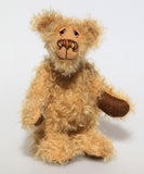 Brodie is a very sweet and friendly artist bear in wildly curly mohair by Barbara-Ann Bears, he stands 8.5 inches/21 tall and is 6 inches 15 cm sitting.  Brodie is made from curly beige gold mohair with brown wool felt paws, he has hand painted glass eyes with eyelids, a carefully embroidered nose and a beaming smile