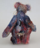 Clarence Sunbeam is a loveable and subtly coloured, one of a kind artist bear, in muted hand dyed mohair by Barbara-Ann Bears, he stands 8 inches/20 cm tall. Clarence Sunbeam is mostly made from a fairly short and sparse mohair hand dyed in indigo, lilac, mauve, rose and ultramarine with splashes of rusty amber.  His face is a very long, feathery pale beige mohair and the backs of his ears and the underside of his tail are a similarly coloured shorter, twirly mohair