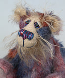 Clarence Sunbeam is mostly made from a fairly short and sparse mohair hand dyed in indigo, lilac, mauve, rose and ultramarine with splashes of rusty amber.  His face is a very long, feathery pale beige mohair and the backs of his ears and the underside of his tail are a similarly coloured shorter, twirly mohair. Clarence Sunbeam has beautiful, hand painted, glass eyes with hand coloured eyelids and carefully embroidered nose all made to incorporate the colours of his mohair and he has a beaming smile