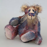 Clarence Sunbeam is a loveable and subtly coloured, one of a kind artist bear, in muted hand dyed mohair by Barbara-Ann Bears, he stands 8 inches/20 cm tall. Clarence Sunbeam is mostly made from a fairly short and sparse mohair hand dyed in indigo, lilac, mauve, rose and ultramarine with splashes of rusty amber.  His face is a very long, feathery pale beige mohair and the backs of his ears and the underside of his tail are a similarly coloured shorter, twirly mohair