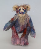 Clarence Sunbeam is a loveable and subtly coloured, one of a kind artist bear, in muted hand dyed mohair by Barbara-Ann Bears, he stands 8 inches/20 cm tall. Clarence Sunbeam is mostly made from a fairly short and sparse mohair hand dyed in indigo, lilac, mauve, rose and ultramarine with splashes of rusty amber.  His face is a very long, feathery pale beige mohair and the backs of his ears and the underside of his tail are a similarly coloured shorter, twirly mohair