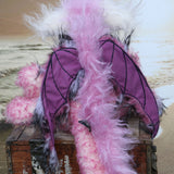 Clarissa The Candyfloss Mountain Dragon a wild yet calm and feminine fluffy pink dragon in gorgeous mohair and faux fur by Barbara Ann Bears, she stands 15 inches( 38 cm) tall and is 11.5 inches (29 cm) sitting. She is about 20 inches (50cm) from nose to tail and has a wingspan of 16 inches (40cm).