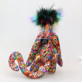 Faustus is mostly made from a very bright and colourful, monstrous cotton fabric. The sides of Faustus' face are a very long pale pink mohair with a dusky lavender-pink backcloth and the top of his nose is a long, fluffy mohair hand dyed yellow. His tummy and the backs of his ears are a long faux fur in bands like a rainbow and on top of his head he has a long black faux fur with plumes of yellow, magenta and teal. Faustus' footpads are made from hand dyed velvet.