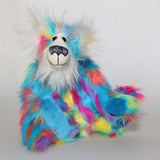 Pedro Piccolo is mostly made from a fairly long and fluffy multi-coloured faux fur in sky blue with flashes of yellow, magenta, orange and mauve. His face, the fronts of his ears and the underside of his tail are a very long and fluffy white mohair. Pedro Piccolo has blue velvet paw pads which complement his colouring perfectly. He has beautiful, hand painted glass eyes with eyelids, a wonderful nose embroidered from individual threads to match his colouring and a charming smile