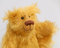 Billy McCubbin is made from a a fluffy medium length gold mohair, that is it would be a medium length mohair on a big bear but on such a little bear it's very long and fluffy. Billy's paw pads are made from the same mohair, trimmed down to the finest stubble.  Billy McCubbin has small spherical glass eyes, that catch the light whichever way you look at him, he has a pert little nose embroidered from fine brown perle cotton and a beaming smile