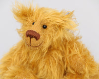 Billy McCubbin is made from a a fluffy medium length gold mohair, that is it would be a medium length mohair on a big bear but on such a little bear it's very long and fluffy. Billy's paw pads are made from the same mohair, trimmed down to the finest stubble.  Billy McCubbin has small spherical glass eyes, that catch the light whichever way you look at him, he has a pert little nose embroidered from fine brown perle cotton and a beaming smile