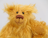 Billy McCubbin is made from a a fluffy medium length gold mohair, that is it would be a medium length mohair on a big bear but on such a little bear it's very long and fluffy. Billy's paw pads are made from the same mohair, trimmed down to the finest stubble.  Billy McCubbin has small spherical glass eyes, that catch the light whichever way you look at him, he has a pert little nose embroidered from fine brown perle cotton and a beaming smile