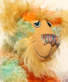 Close-up of Bossa Nova's face showing his long golden fur, his beautiful hand painted eyes, his multicoloured nose and broad smile. Bossa Nova is a 21 inch colourful, one of a kind, artist teddy bear in gorgeous hand dyed mohair by Barbara-Ann Bears