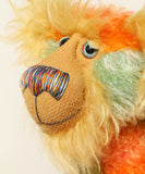 Close-up of Bossa Nova's face showing his long golden fur, his beautiful hand painted eyes, his multicoloured nose and broad smile. Bossa Nova is a 21 inch colourful, one of a kind, artist teddy bear in gorgeous hand dyed mohair by Barbara-Ann Bears