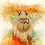 Close-up of Bossa Nova's face showing his long golden fur, his beautiful hand painted eyes, his multicoloured nose and broad smile. Bossa Nova is a 21 inch colourful, one of a kind, artist teddy bear in gorgeous hand dyed mohair by Barbara-Ann Bears