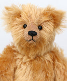 Close-up of Bruce Fettlewell is a cuddly little traditional one of a kind artist bear in antique gold German mohair with a soft texture on a light background