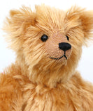 Close-up of Bruce Fettlewell is a cuddly little traditional one of a kind artist bear in antique gold German mohair with a soft texture on a light background
