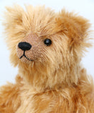 close up of Bruce Fettlewell is a cuddly little traditional one of a kind artist bear in antique gold German mohair with a soft texture on a light background