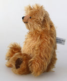 Buddy in profile, a sweet antique gold teddy bear on a white background