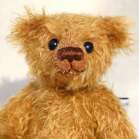 Bunbeary's face. Bunbeary is a well proportioned yet slightly raggedy traditional teddy bear. Bunbeary is made from beautiful distressed antique gold German mohair which has a warm tan backing, with wool felt paw pads, boot button eyes and a sweet smile.