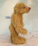 Bunbeary standing, showing his profle. Bunbeary is a well proportioned yet slightly raggedy traditional teddy bear. Bunbeary is made from beautiful distressed antique gold German mohair which has a warm tan backing, with wool felt paw pads, boot button eyes and a sweet smile.