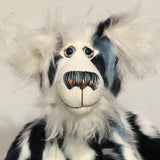 A close up of Charleston's face, showing his beautiful long white fluffy mohair, his large hand painted glass eyes, his multi-coloured nose and sweet smile