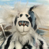 A close up of Charleston's face, showing his beautiful long white fluffy mohair, his large hand painted glass eyes, his multi-coloured nose and sweet smile