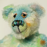 Close-up of Colin Cockles a colourful hand dyed mohair teddy bear with a rainbow-striped nose on a light background