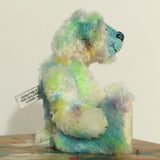 Profile of Colin Cockles a colourful hand dyed mohair teddy bear sitting on a wooden surface
