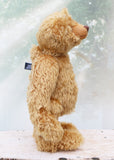 Brown teddy bear standing on a wooden surface with a blurred background