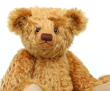 Close up of Cuthbert, a one of a kind antique gold teddy bear sitting on a white background